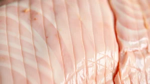 Close-up of scored pork belly skin with crosshatch pattern, raw and glistening with rendered fat, ready for cooking, professional butcher preparation